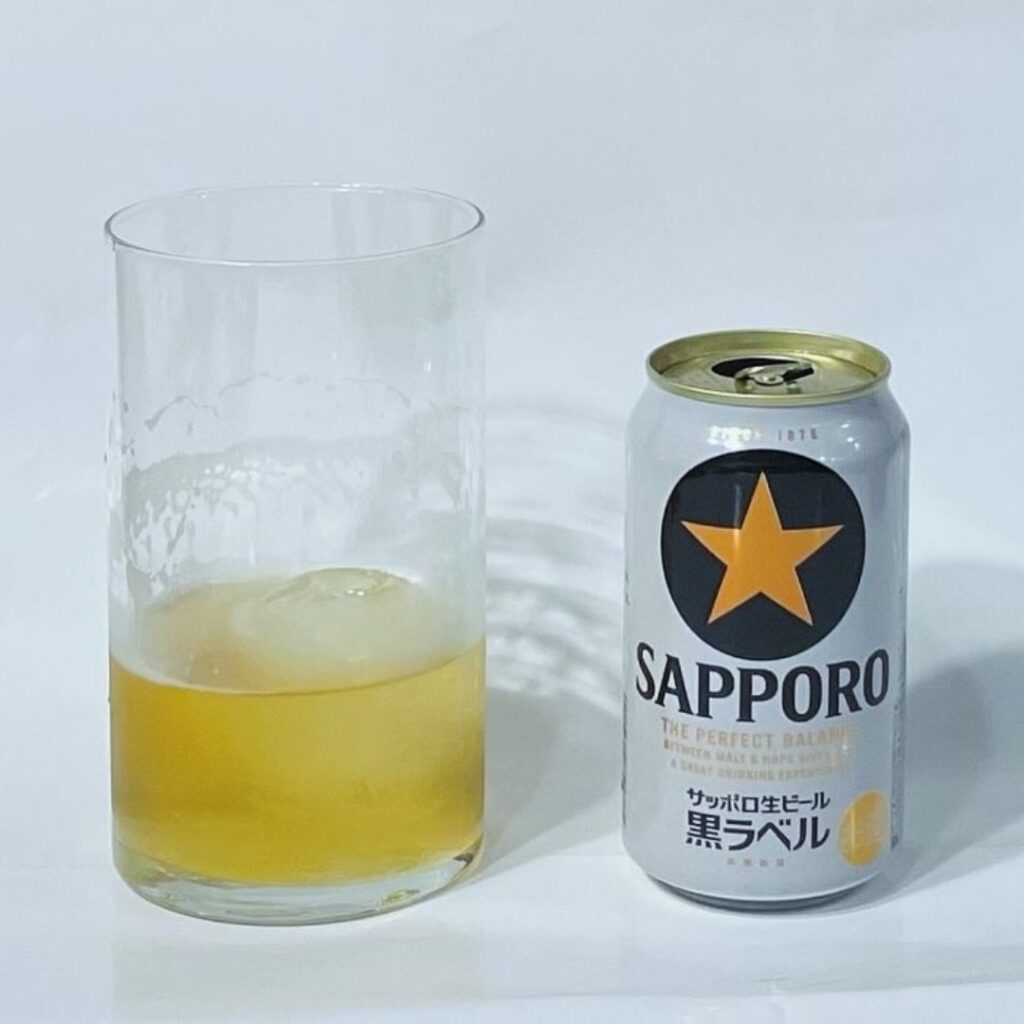 半分飲み干した、氷入りのビールとサッポロ黒ラベル缶。