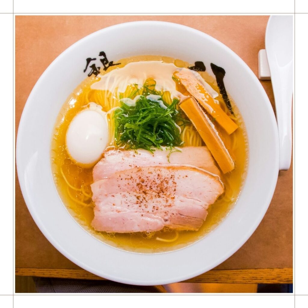 テーブルに置かれたラーメン。
透明のスープにチャーシュー、メンマ、玉子、ネギがのっている。