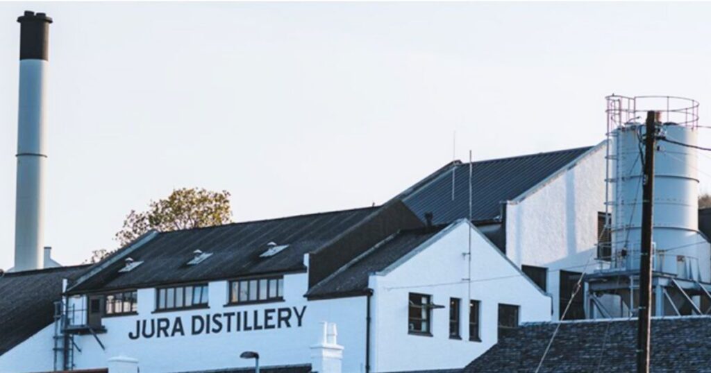 ジュラ蒸留所の外観。
白い建物の壁面に「JURA DISTILLERY」のロゴが見える。