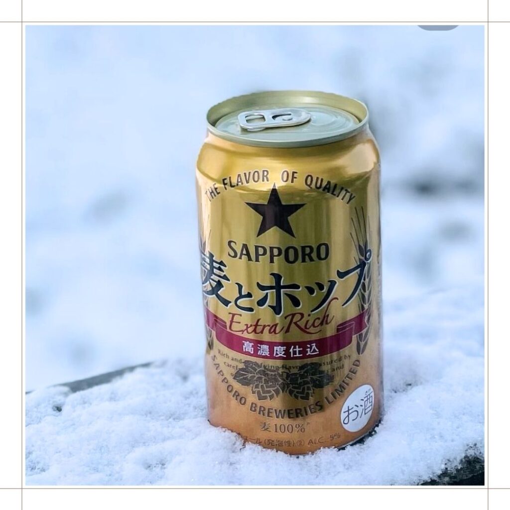 サッポロ麦とホップ缶が、雪の積もった塀の上に置かれている。